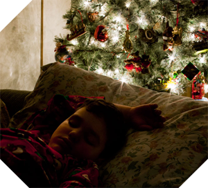 boy asleep next to Christmas tree